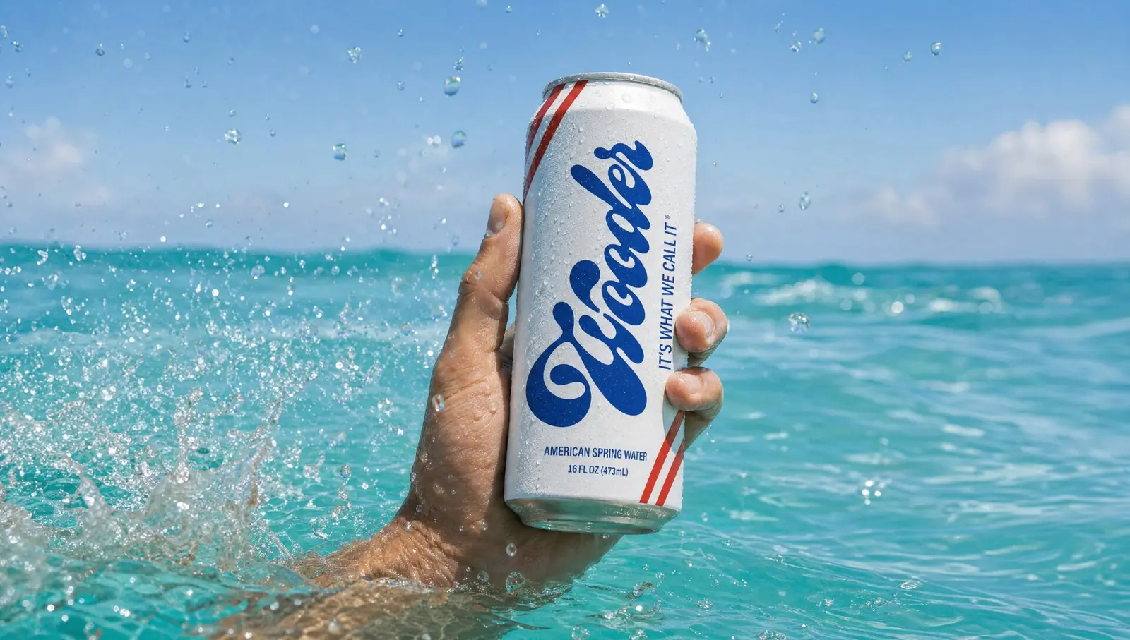 Hand holding a Wooder can rising from turquoise ocean water